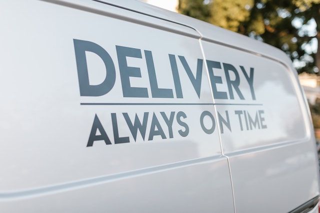 Close up side shot of a white delivery vehicle with a big print "DELIVERY ALWAYS ON TIME"